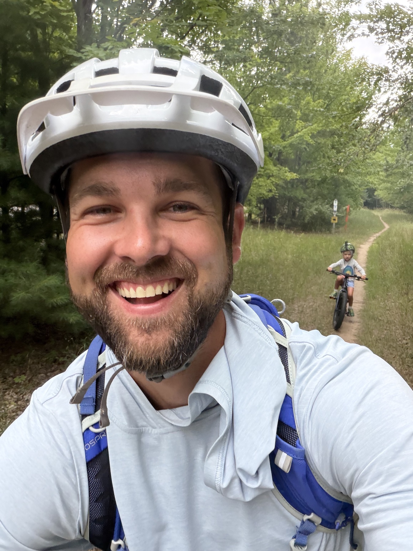 Mike smiling during a bike ride on a wooded trail